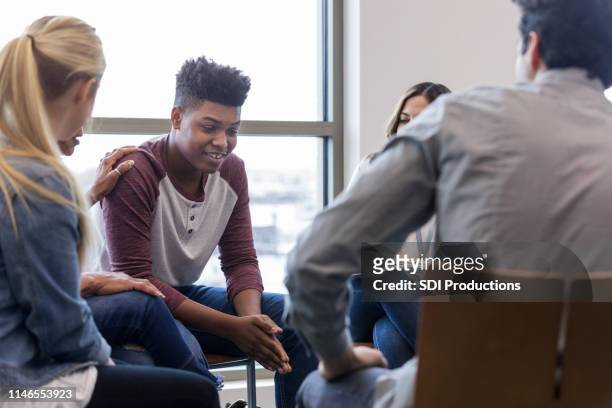 diverse group watches teen boy's reactions - teen group therapy stock pictures, royalty-free photos & images
