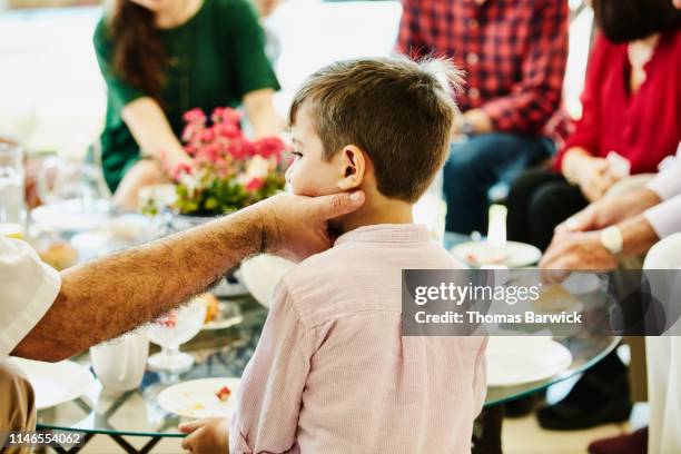 uncle squeezing young nephews face during family party - uncle nephew stock pictures, royalty-free photos & images