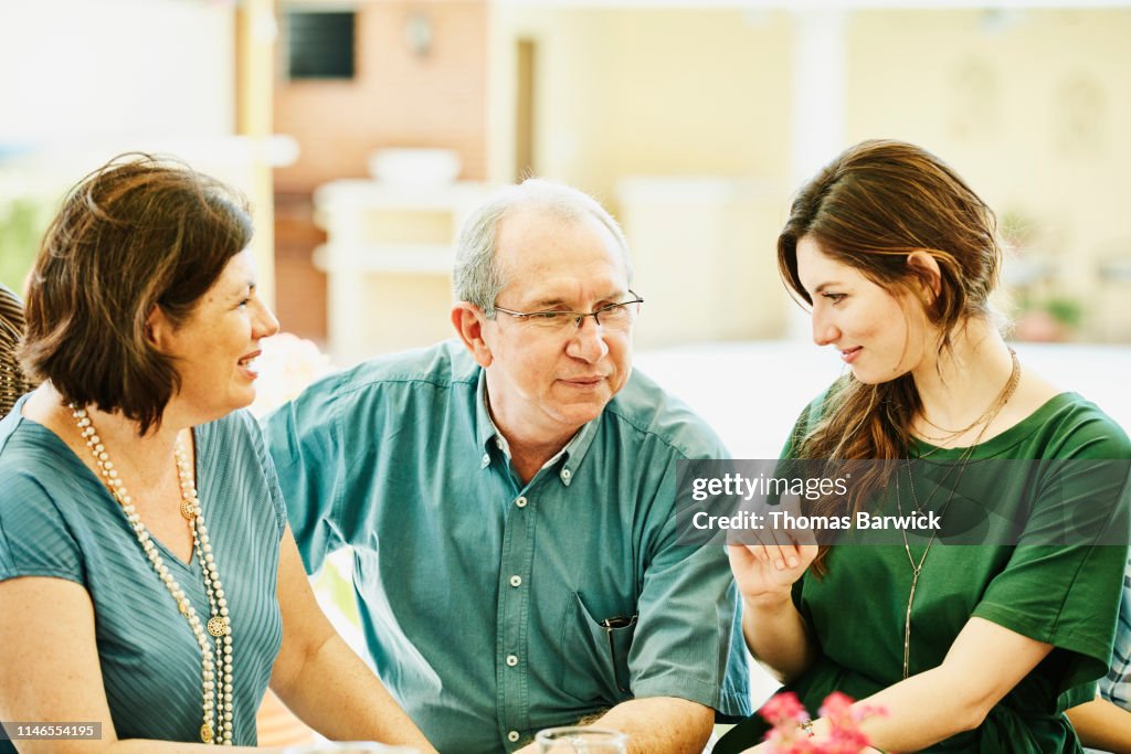 Adult daughter in discussion with mother and father during outdoor family brunch