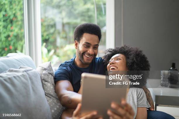 couple having fun using digital tablet - couple with ipad in home stock pictures, royalty-free photos & images