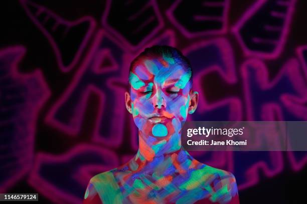 portrait of beautiful woman with fluorescent make up in ulteaviolet light - pittura del corpo foto e immagini stock