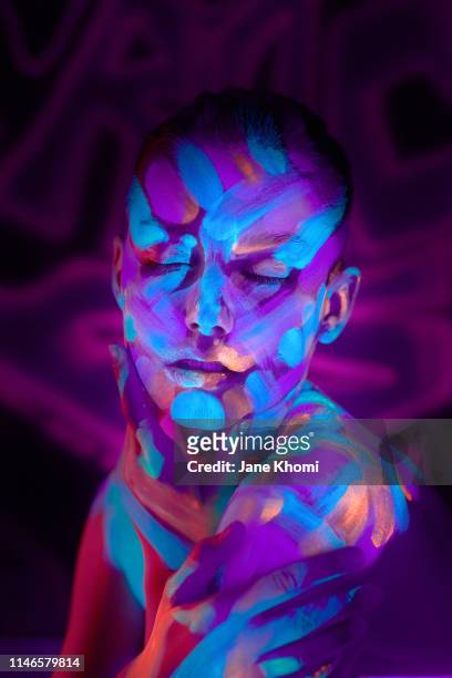 portrait of beautiful woman with fluorescent make up in ulteaviolet light - körperbemalung stock-fotos und bilder