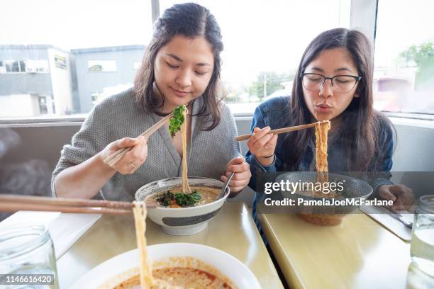 pov, gemengde-etnische zusters eten veganistisch japanse ramen noodle soep in diner - asian family cafe stockfoto's en -beelden