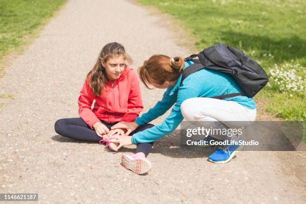 mother helping her daughter with a sprained ankle - twisted ankle stock pictures, royalty-free photos & images