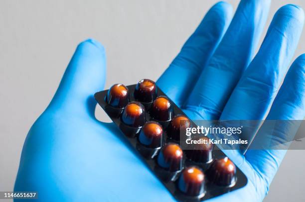 a young person with blue gloves is holding a pack of medicine - garment factory stock pictures, royalty-free photos & images