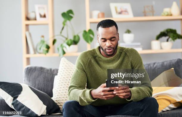 het verzenden van een paar sms-berichten - african on phone stockfoto's en -beelden