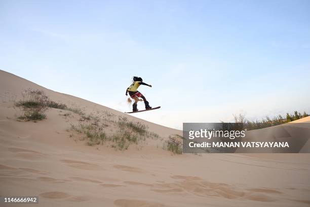 This photograph taken on April 24, 2019 shows Nguyen Thai Binh riding down sand dunes on his snowboard in the southern Vietnamese town of Mui Ne. -...