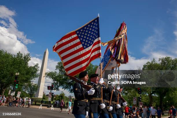 United States Army Soldiers carry flags and streamers along Constitution Avenue during the National Memorial Day Parade in Washington DC.