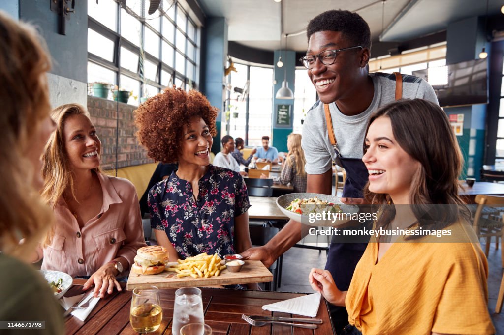 Camarero sirviendo grupo de mujeres amigas reunión para bebidas y comida en el restaurante