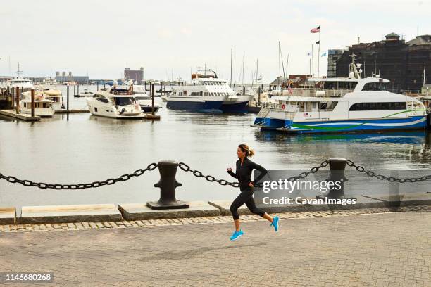 a woman runs alongside boston harbor. - boston harbour stock pictures, royalty-free photos & images