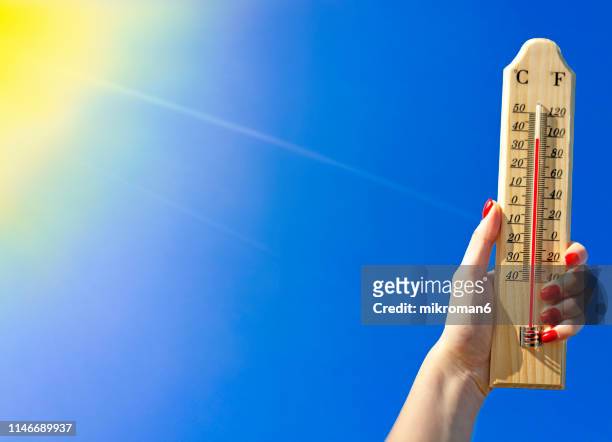 thermometer against a bright blue sky - calor fotografías e imágenes de stock