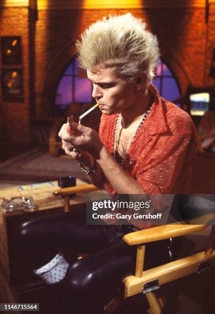 British Rock musician Billy Idol lights a cigarette during an interview at MTV Studios, New York, New York, December 6, 1982.