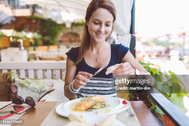 woman eating seafood in restaurant - salmon seafood stock pictures, royalty-free photos & images