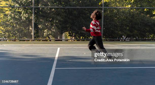 7-years-old boy playing on the tennis court in the park in the sunny warm spring day. - boys only caucasian ethnicity 6 7 years stock pictures, royalty-free photos & images