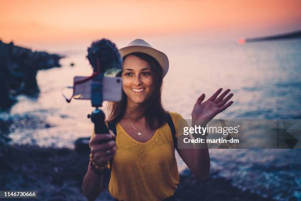 mujer joven que vlogging de vacaciones en la playa - reportaje imágenes fotografías e imágenes de stock