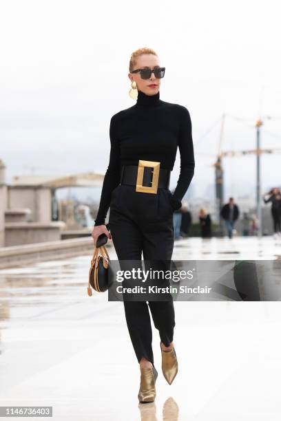 Fashion consultant Elina Halimi wears a Celine belt and sunglasses, Saint Laurent trousers, Louis Vuitton bag on March 02, 2019 in Paris, France.