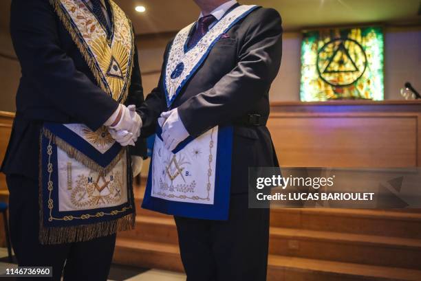 Two French freemasons shake hands inside a masonic temple in Suresnes, west of Paris, on May 27, 2019.