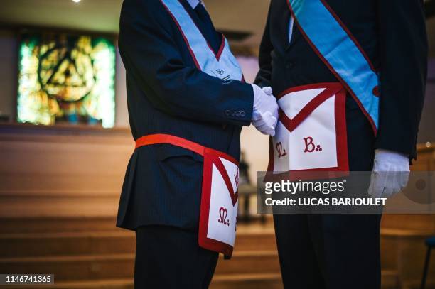 Two French freemasons shake hands inside a masonic temple in Suresnes, west of Paris, on May 27, 2019.
