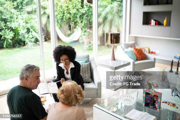 advisor showing and discussing some data with her clients - advice home imagens e fotografias de stock