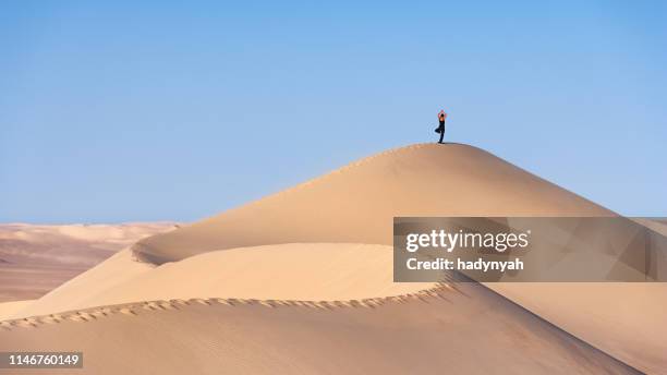 touriste féminin pratiquant le yoga sur le dessus de sandune, désert du sahara - désert du sahara photos et images de collection