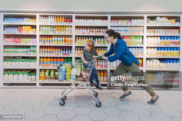 mother and child racing through supermarket aisle - excited run stock pictures, royalty-free photos & images