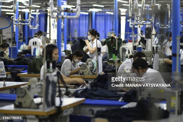 This photograph taken on May 24, 2019 shows garment factory workers making men's suits in a factory in Hanoi. From socks and sneakers to washing...