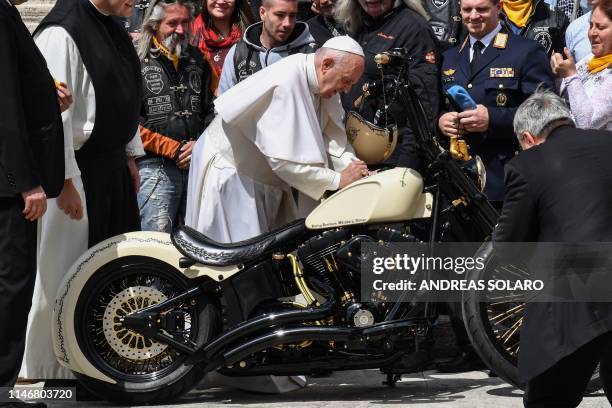 Pope Francis signs an Harley Davidson motorcycle next to members of Christian motorcycle group during his weekly general audience on May 29, 2019 at...
