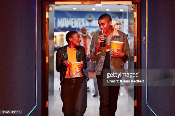 happy young friends talking while walking in corridor at movie theater - dating stock-fotos und bilder
