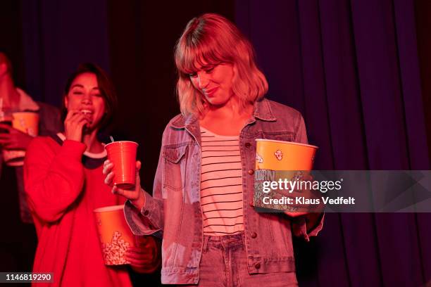 low angle view of smiling young female friends with snacks and soda entering cinema hall in movie theater - australians in film hosts the premiere of that sugar film arrivals stockfoto's en -beelden