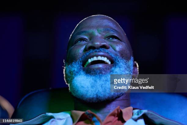 low angle view of happy bearded man watching movie in theater - bald man stockfoto's en -beelden
