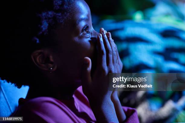 shocked girl covering mouth while watching thriller movie in theater - pre event stock pictures, royalty-free photos & images