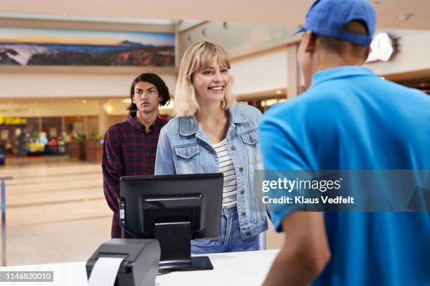 smiling woman buying tickets in theater - movie counter stock pictures, royalty-free photos & images