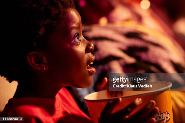 shocked girl with popcorn watching thriller movie in cinema hall at theater - children theatre foto e immagini stock