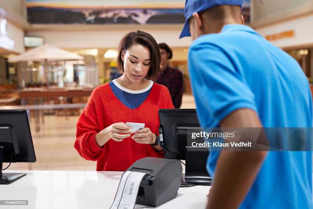 Woman paying through credit card at ticket counter