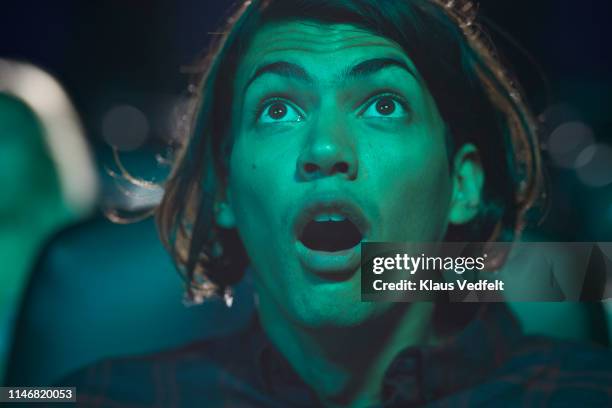 shocked young man watching horror movie in cinema hall at theater - filme de terror imagens e fotografias de stock