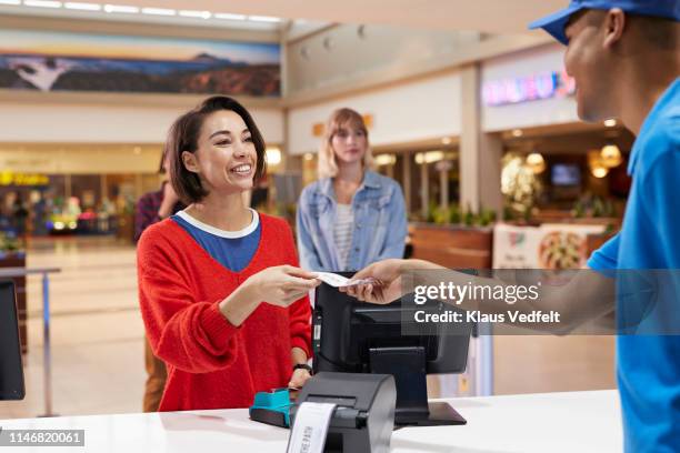 cashier giving tickets to smiling woman - ticket counter fotografías e imágenes de stock