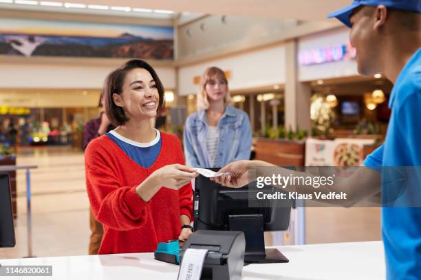 cashier giving tickets to smiling woman - cinema ticket stock pictures, royalty-free photos & images