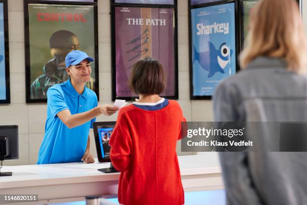 cashier selling tickets to woman in theater - movie counter stock pictures, royalty-free photos & images