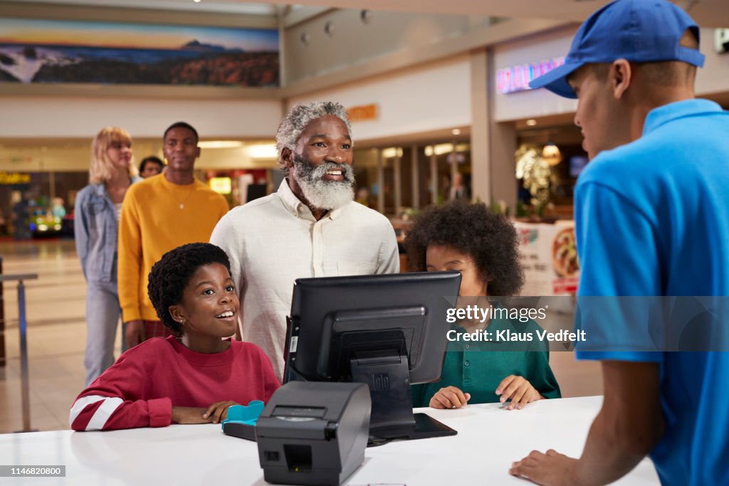 Excited family buying movie tickets at theater