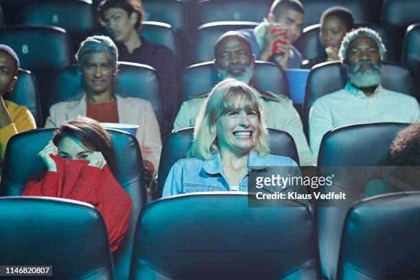 frightened multi-ethnic men and women watching horror movie in cinema hall of theater - movie theatre audience stock-fotos und bilder
