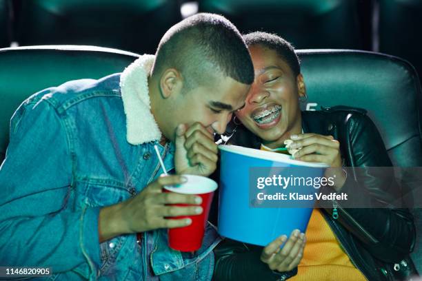 cheerful young friends laughing while watching funny movie together at cinema theater - black theatre stock pictures, royalty-free photos & images