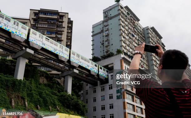 Tourist takes photos of a light-rail train driving through a residential building at Liziba Station on the third day of the 4-day International...