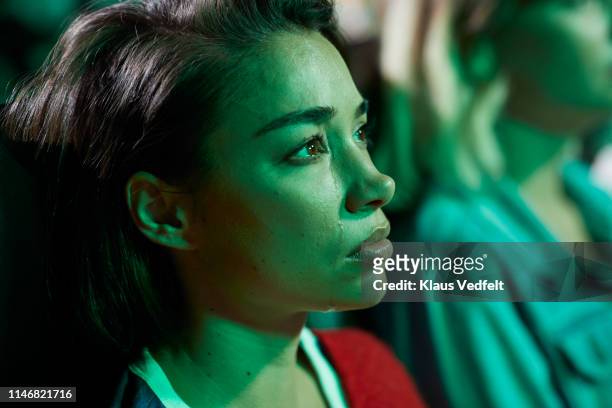 close-up of young woman crying while watching movie in cinema hall - teardrop foto e immagini stock
