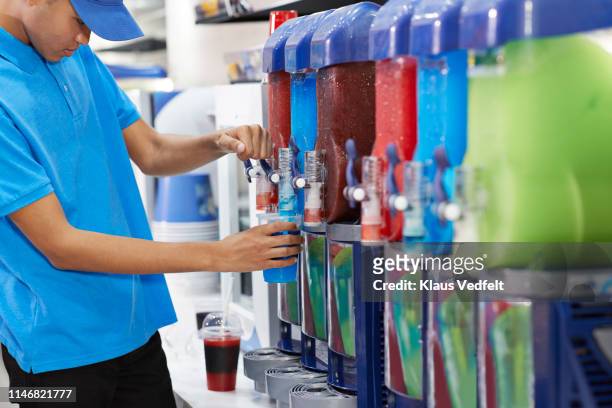 male employee filling soda in cup from machinery - スラッシュ ストックフォトと画像