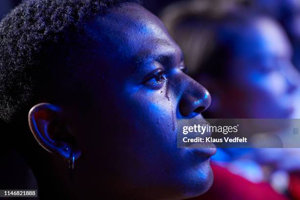 side view of young man crying while watching movie in cinema hall - huilen stockfoto's en -beelden