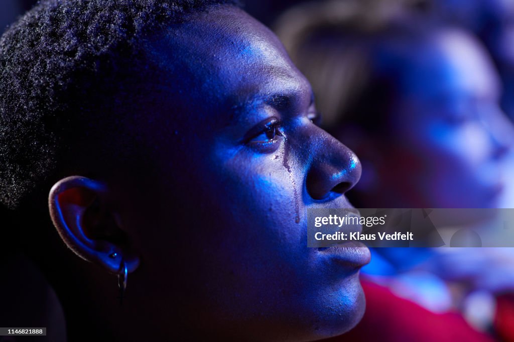 Side view of young man crying while watching movie in cinema hall