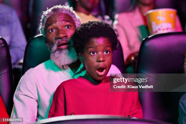 shocked girl watching horror movie with father in cinema hall - horror movie stock pictures, royalty-free photos & images