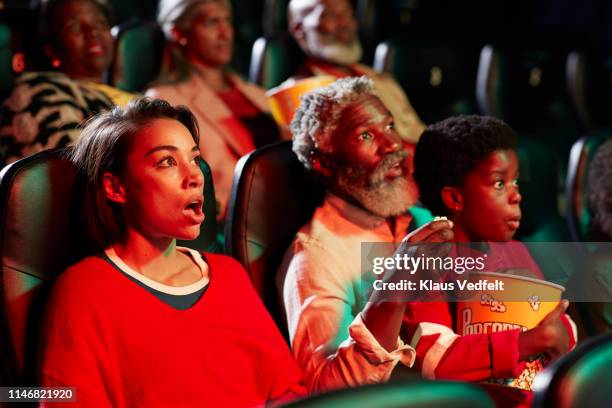 surprised young woman watching horror movie by spectators in theater - horror movie ストックフォトと画像