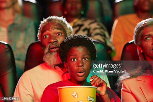shocked man watching horror movie with girl in cinema hall - children theater stock pictures, royalty-free photos & images