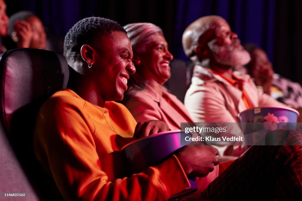 Cheerful men and women watching comedy film in theater